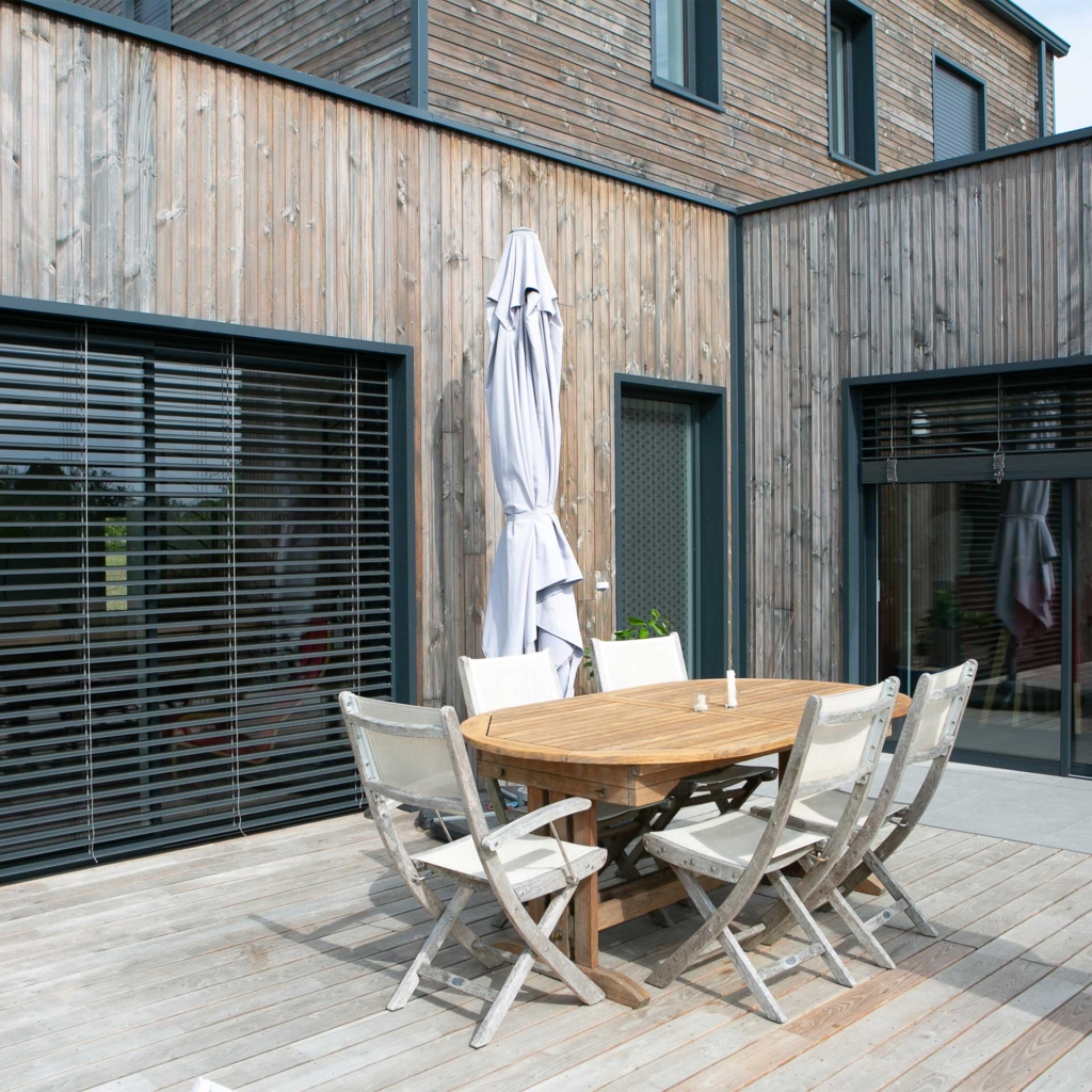 Terrasse d’une maison ossature bois à Beaufort-en-Anjou avec bardage naturel